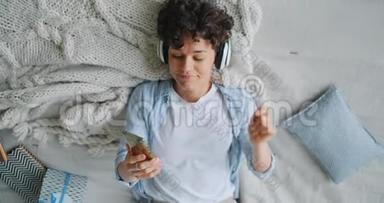 女孩在床上使用智能手机和耳机听音乐的慢动作